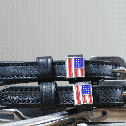 Close-up of American flag charms and silver buckles on black leather spur straps