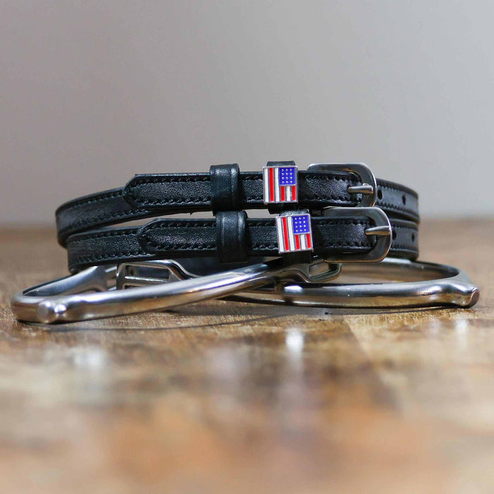Coiled black leather spur straps and a silver spur on wood with US flag charms