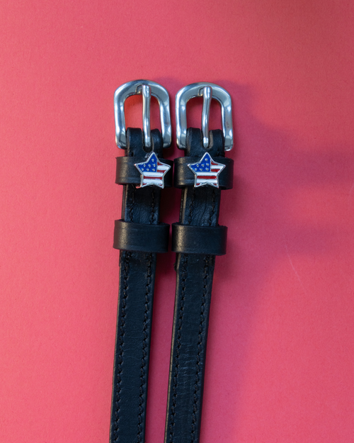 Pair of black leather American star spur straps with silver buckles on coral