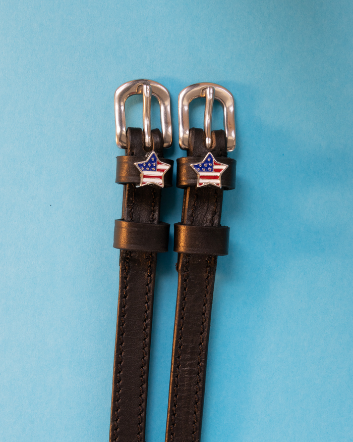 Brown leather American star spur straps with silver buckles on a light blue background
