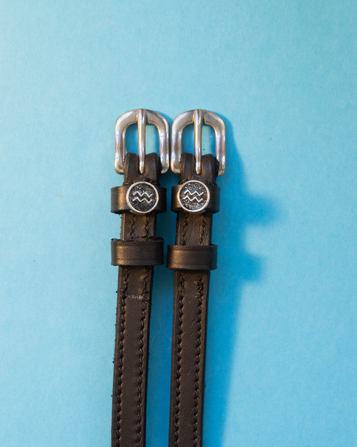 Black leather ManeJane spur straps with round Aquarius zodiac charms on light blue
