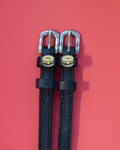 Pair of black leather ManeJane spur straps with bagel sandwich charms on pink