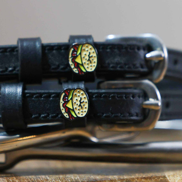 Close-up of an egg bagel sandwich charm on a black leather spur strap keeper