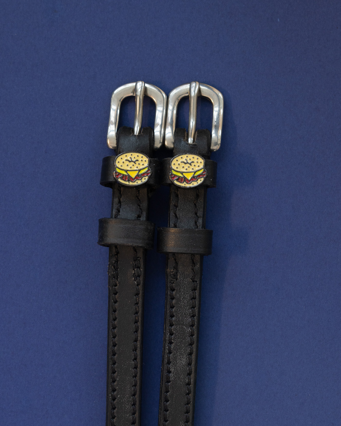 Pair of black leather bagel sandwich spur straps on a navy background