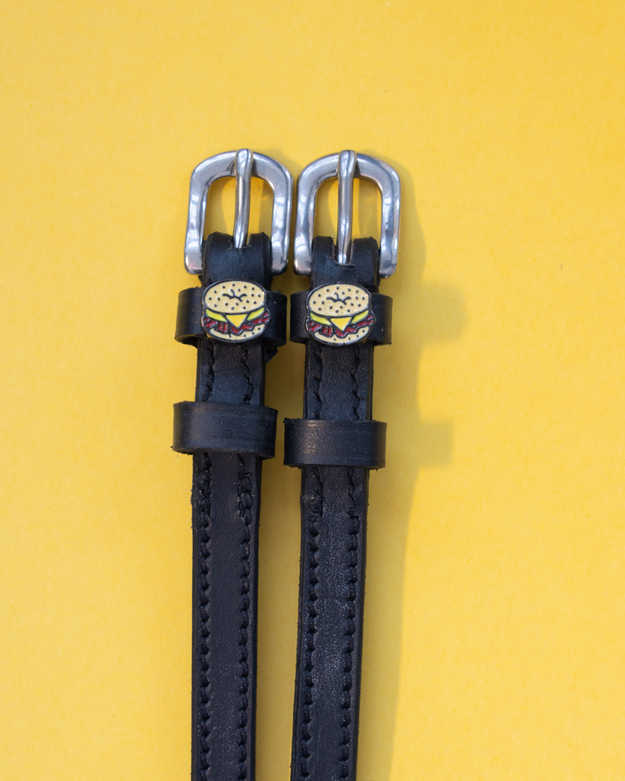 Black leather bagel sandwich spur straps on a yellow background