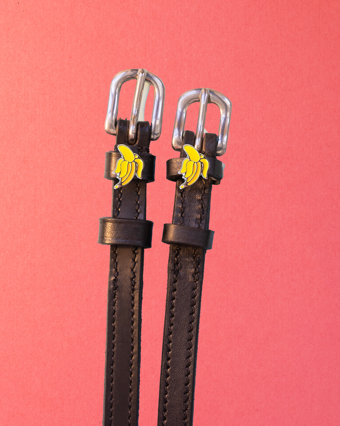 Black leather ManeJane Banana spur straps with silver buckles and banana charms on coral