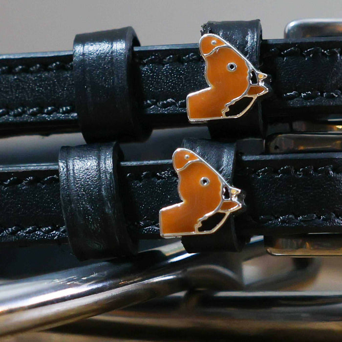 Close-up of tan horse-head charms on black leather ManeJane spur strap keepers