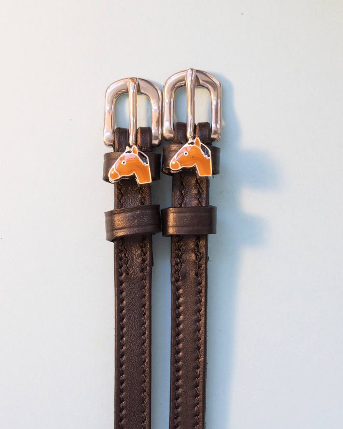 Brown leather spur straps with silver buckles and tan horse-head charms