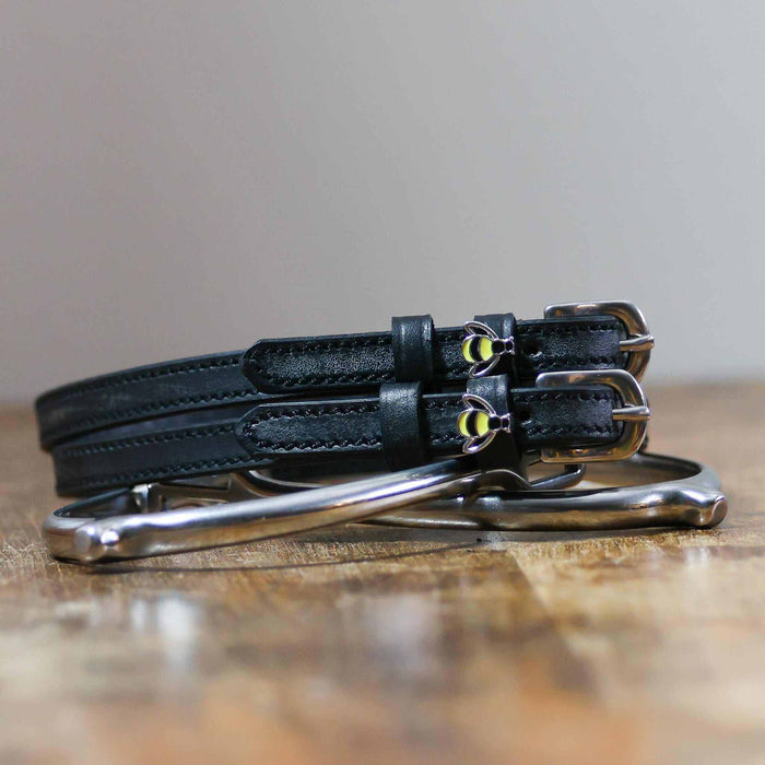 Black bee spur straps coiled on a silver stirrup on a wooden table