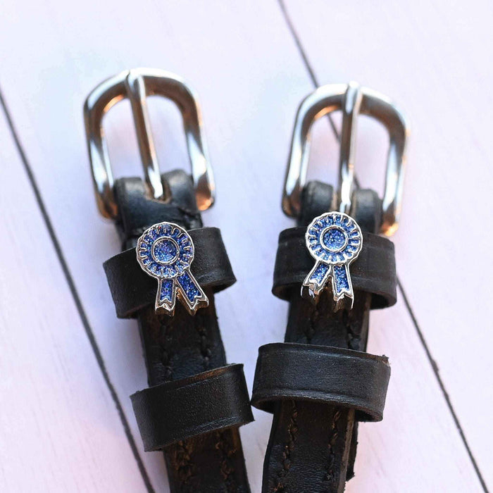 Blue ribbon rosette spur straps with silver buckles on white-painted wood planks