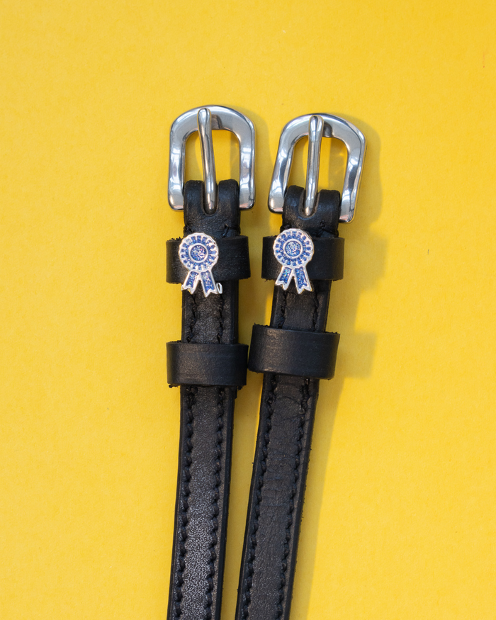 Black leather blue-ribbon rosette spur straps with silver buckles on yellow