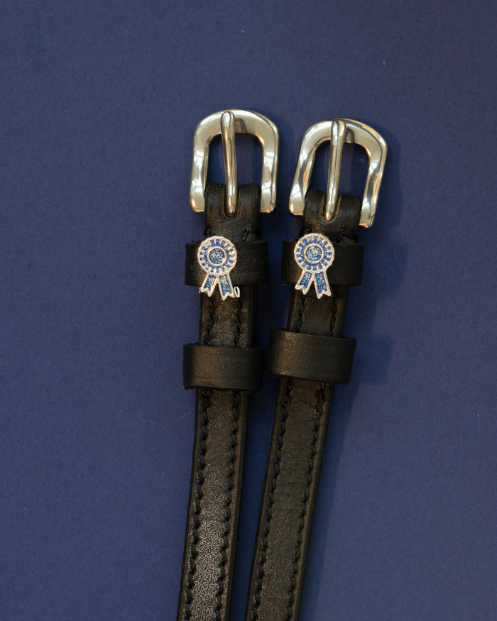 ManeJane blue-ribbon spur straps with silver buckles laid flat on navy blue
