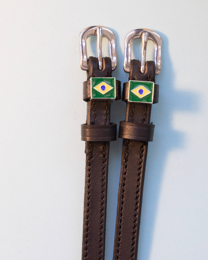 Brown leather ManeJane Brazil flag spur straps with silver buckles on pale grey
