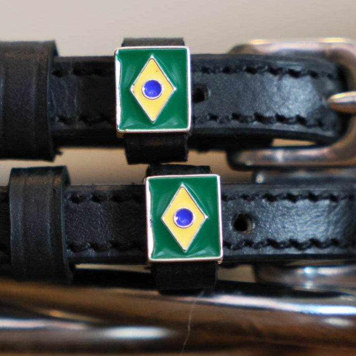 Close-up of Brazilian flag charms on black leather spur strap keepers by a stirrup