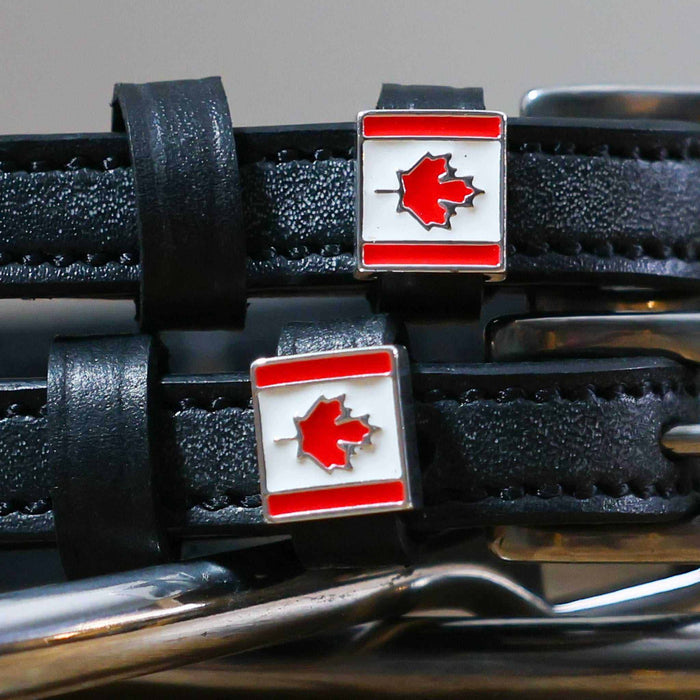 Close-up of Canadian maple-leaf flag charms on black leather ManeJane spur strap keepers