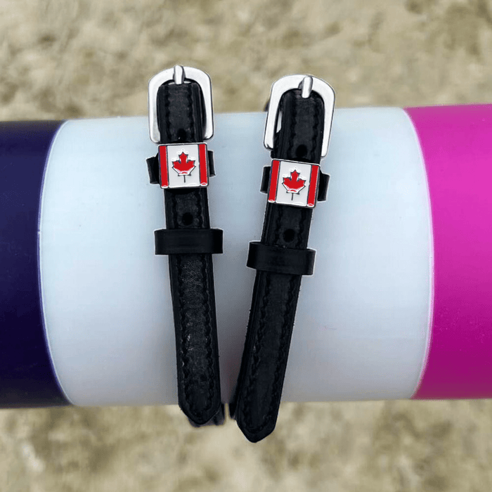 Black leather Canadian flag spur straps draped over a white jump pole