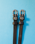 Black leather ManeJane spur straps with round Capricorn zodiac charms on light blue