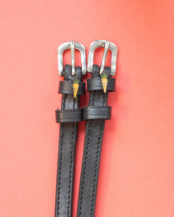 Black leather ManeJane spur straps with silver buckles and enamel carrot charms on coral
