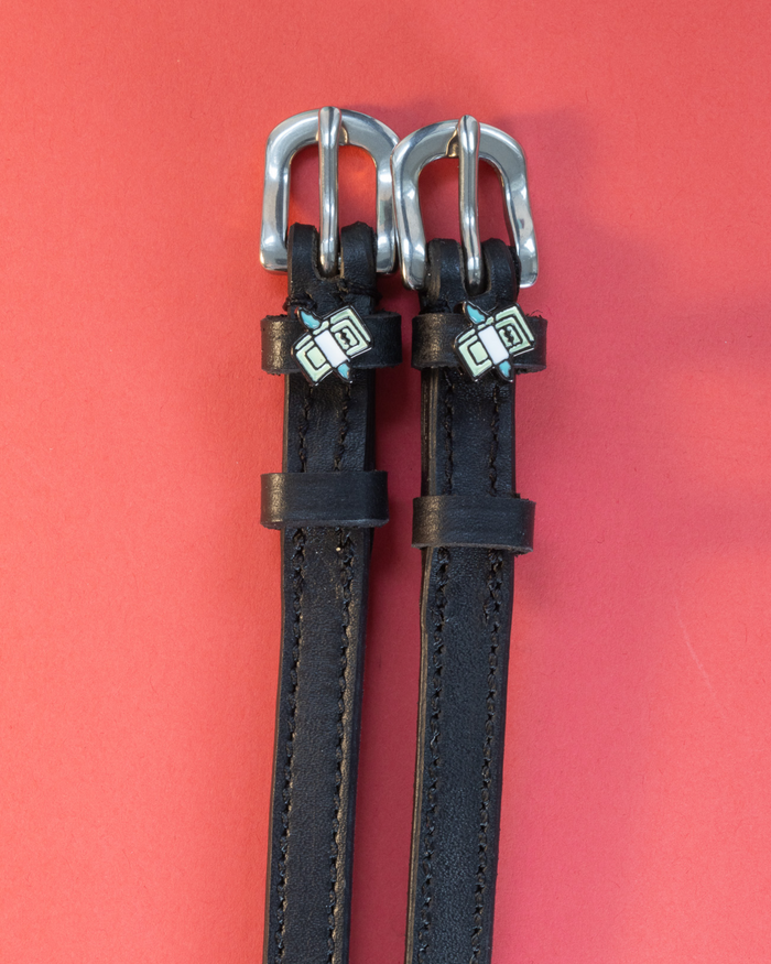 Pair of black leather cash money spur straps on a coral background