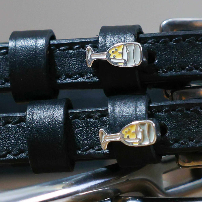Close-up of enamel champagne-flute charms on black leather spur strap keepers