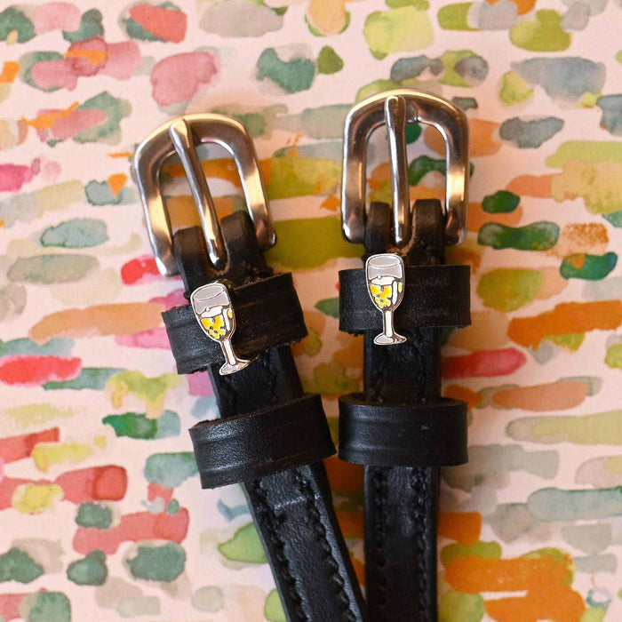 Champagne-charm spur straps on a watercolor confetti backdrop, buckle close-up