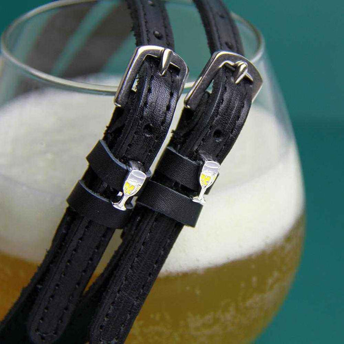 ManeJane champagne spur straps draped over a glass of bubbly on teal