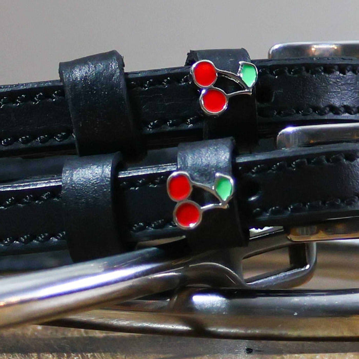 Close-up of a red-and-green enamel cherry charm on a black leather spur strap keeper