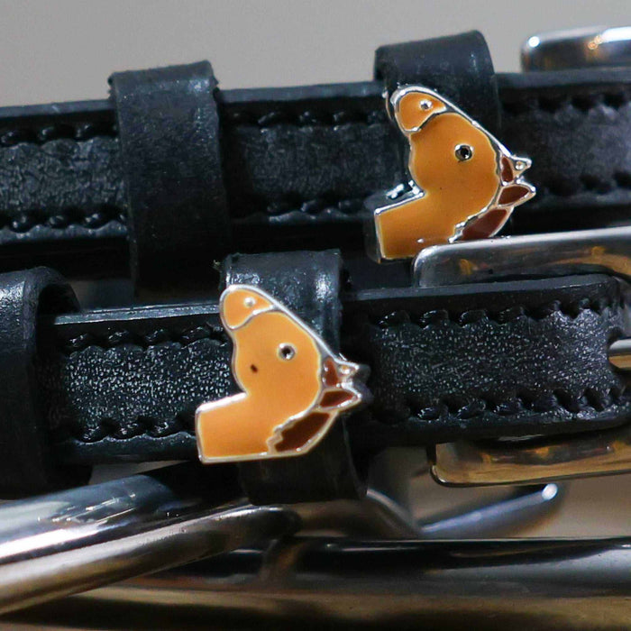 Close-up of chestnut horse-head charms and silver buckles on black spur straps