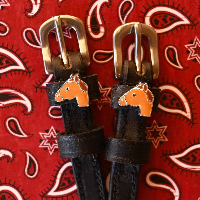 Chestnut horse-head charms on black spur straps over a red paisley bandana
