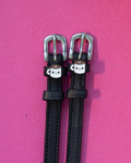 Black leather ManeJane spur straps with smiling coffee-mug charms on pink