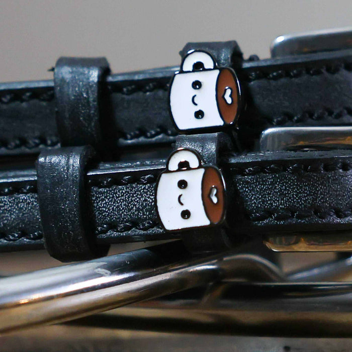Close-up of kawaii coffee-mug charms on black leather spur strap keepers