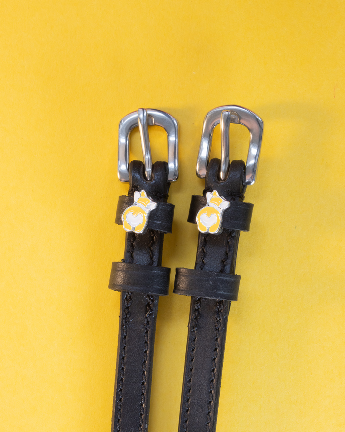 Pair of black leather ManeJane spur straps with corgi butt charms on yellow