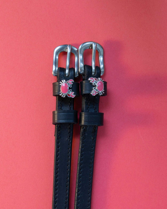 Crabbin' ManeJane spur straps with the signature Crabbin' charm, shown on a coral background