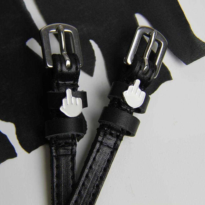 Close-up of black Da Bird spur straps and emoji charms on white with black fabric, ManeJane