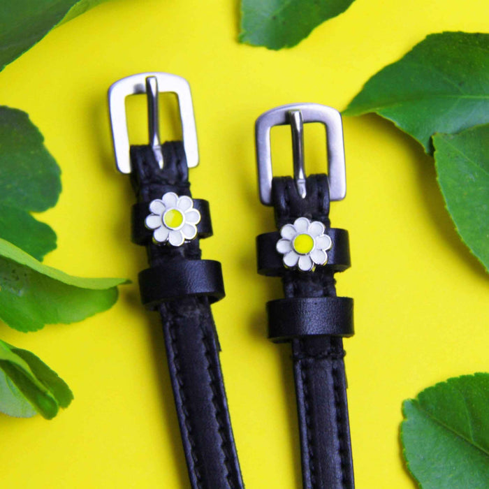 Daisy flower spur straps with silver buckles on yellow framed by green leaves