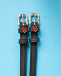 Black leather ManeJane spur straps with red Devil heart charms on light blue