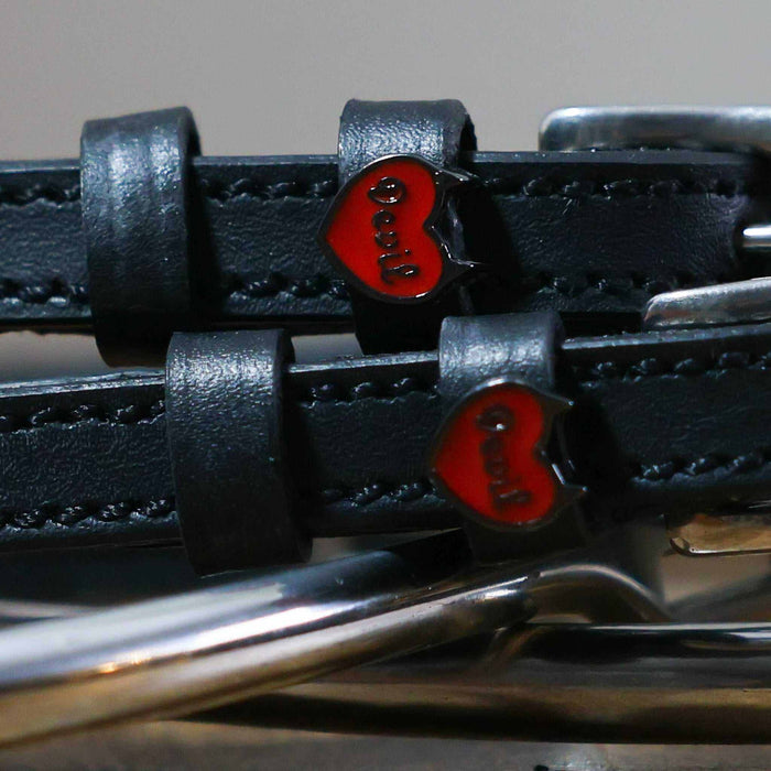 Close-up of red enamel Devil heart charms on black leather spur strap keepers