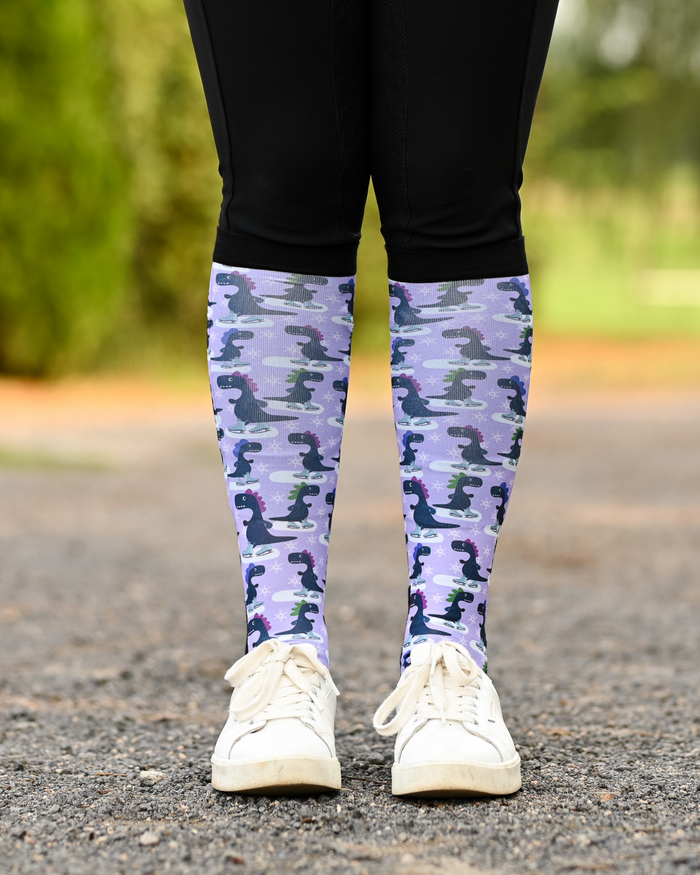 Dino-skate riding boot socks styled over breeches, lavender with dinosaurs skating on ice