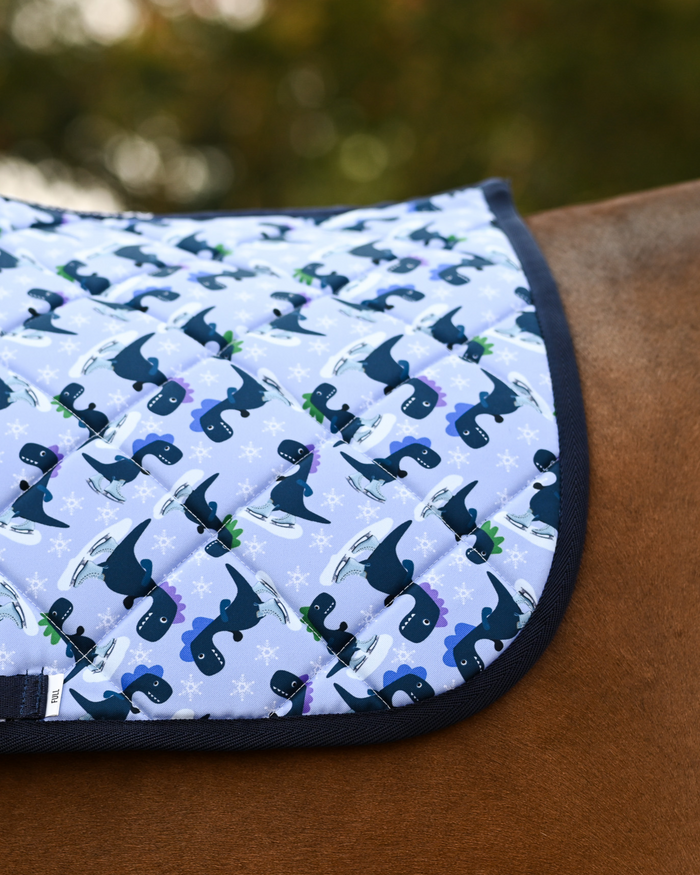 Close-up of the Dino-skate print: navy and green dinosaurs on ice skates over pale periwinkle quilting