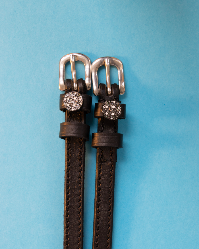 Dark brown leather disco ball spur straps with silver buckles on a light blue background