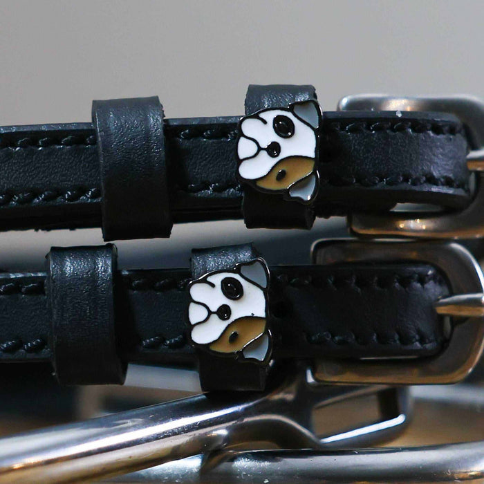 Close-up of white-and-tan bulldog head charms on black leather spur straps