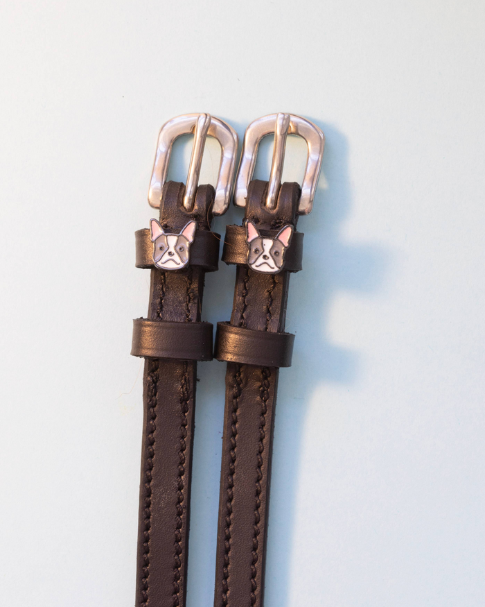 Brown leather ManeJane Frenchie spur straps with silver buckles on pale grey