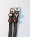 Brown leather ManeJane Frenchie spur straps with silver buckles on pale grey
