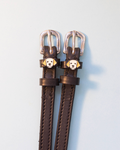 Dark brown Golden Retriever spur straps with silver buckles and dog face charms on grey