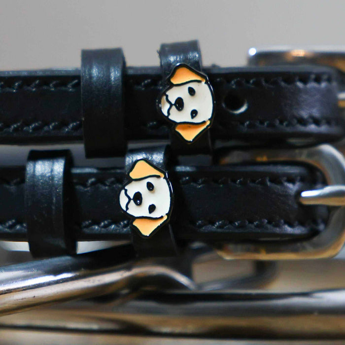 Close-up of golden retriever face charms on black leather spur straps over spur hardware