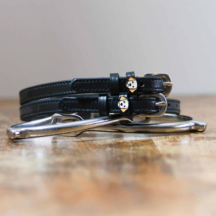 ManeJane Golden Retriever spur straps coiled beside silver spurs on a wooden table