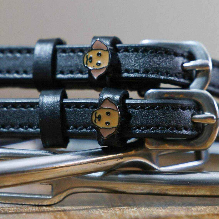 Close-up of tan Labrador dog face charms on black leather ManeJane spur straps