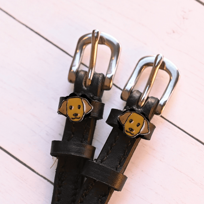 Angled close-up of golden Labrador dog charms on black leather ManeJane spur straps