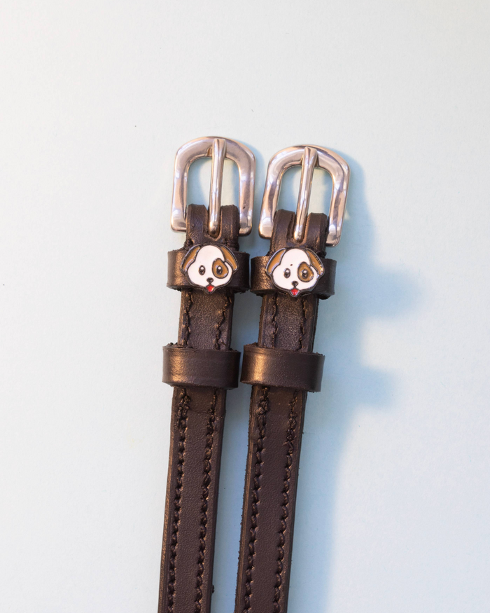 Pair of brown leather ManeJane spur straps with puppy face charms on grey