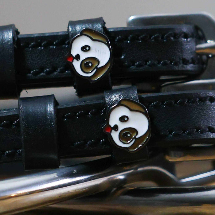 Close-up of a white-and-brown puppy face charm on a black leather spur strap